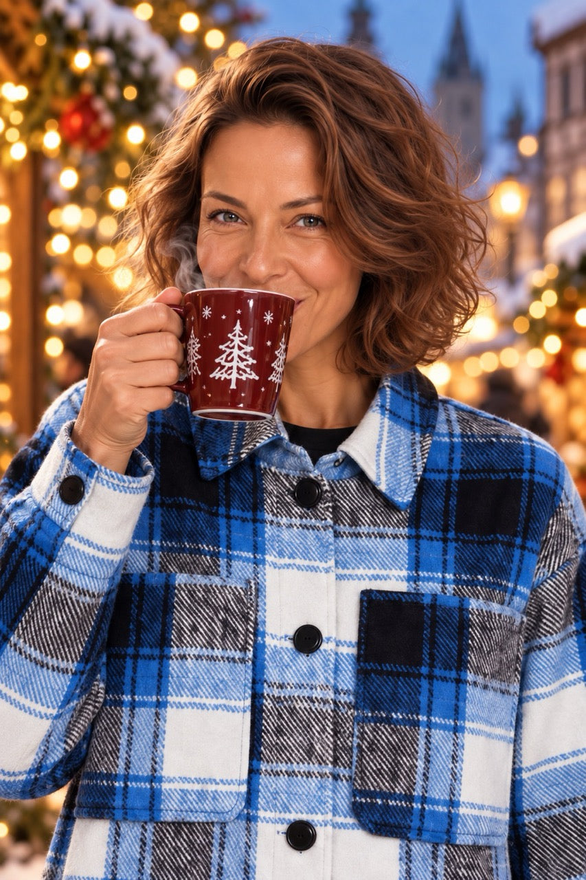 Close-up of a model wearing the ICHI IHELISABETTE blue checked jacket and sipping from a red mug at a Christmas market.