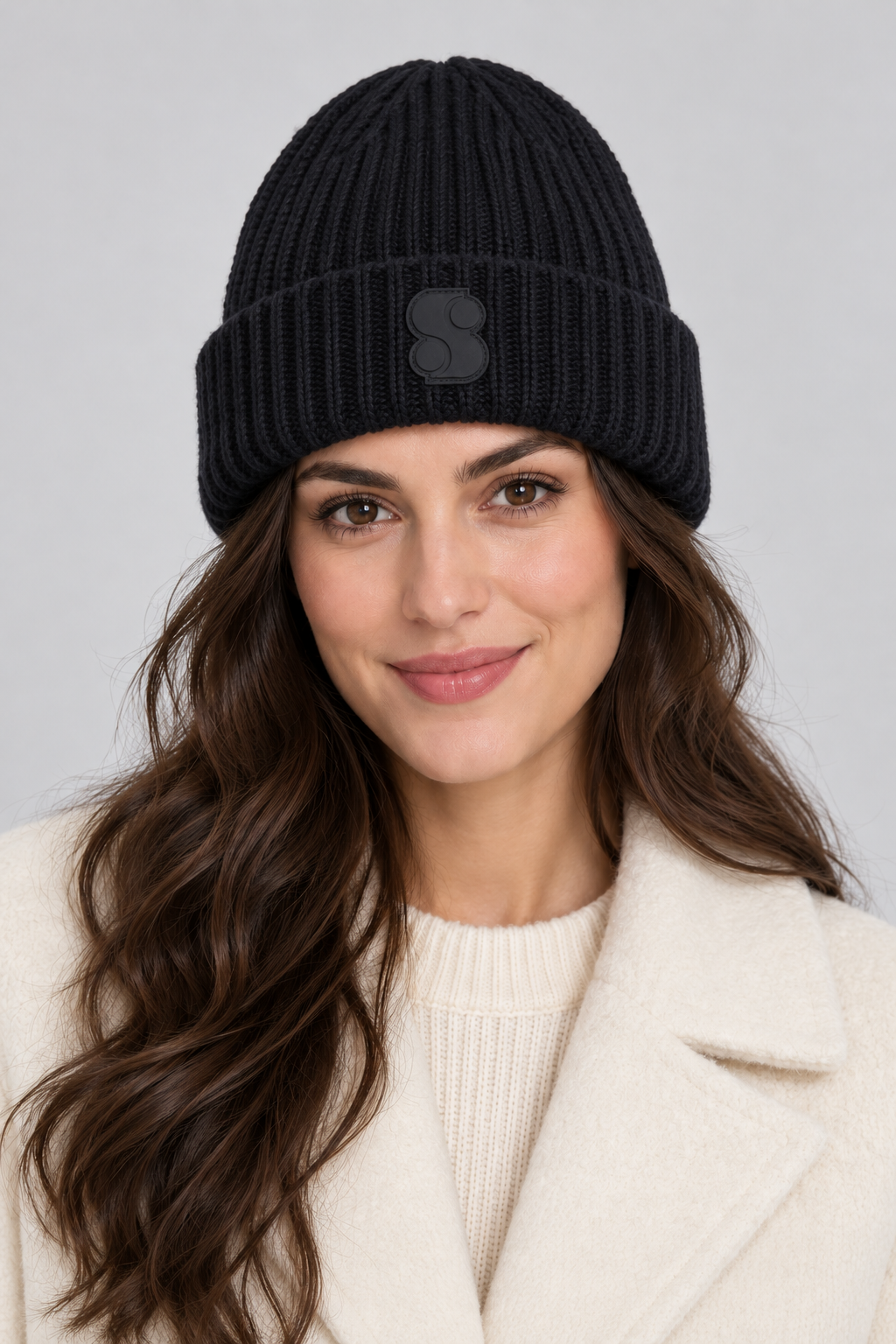 Studio portrait of a woman wearing the s.Oliver navy ribbed beanie with S patch and a cream coat