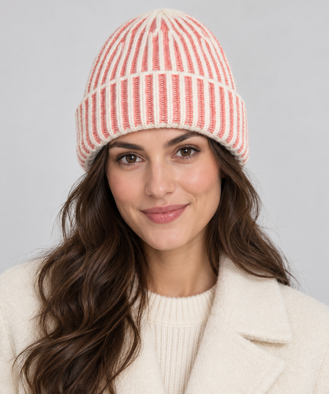 Woman wearing an s.Oliver papaya and cream striped beanie with a cream coat against a neutral studio background