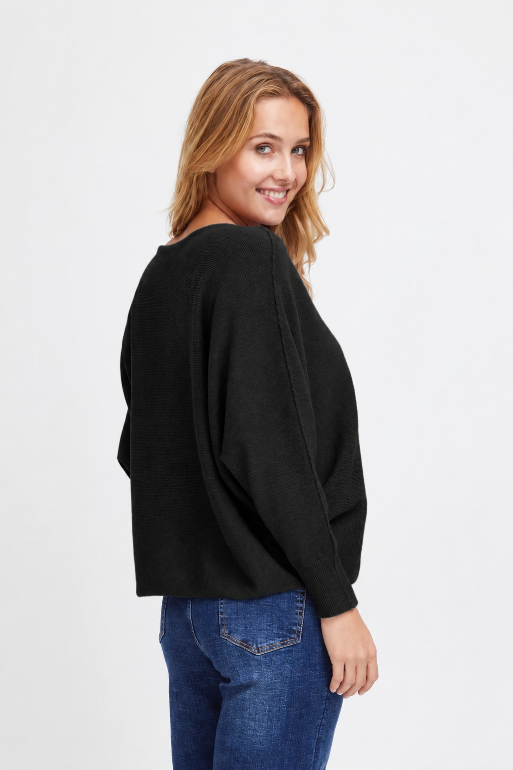 Three-quarter back view of the Sorbet Basil black knit jumper worn with blue jeans